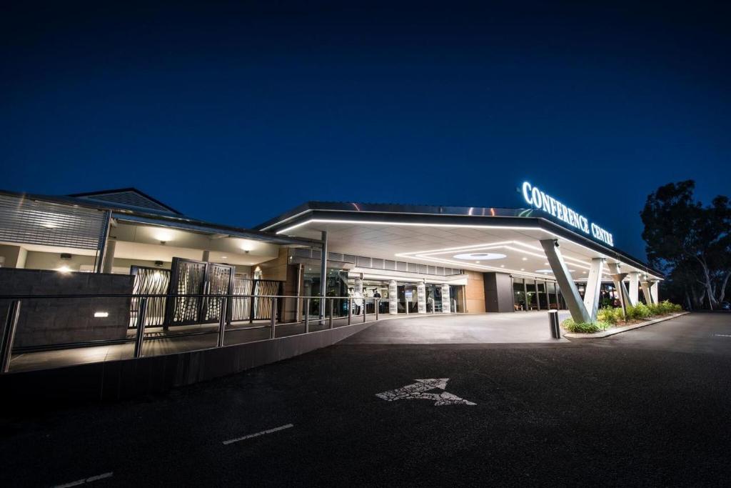 Redlands Rugby Union Club Modern conference center building with illuminated entrance at night, featuring a covered drop-off area and large glass windows.