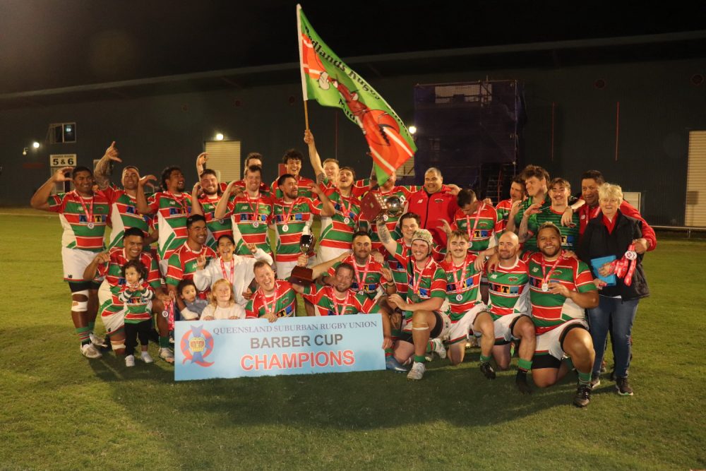 Redlands Rugby Union Club A rugby team poses on a field at night, celebrating with a banner reading 